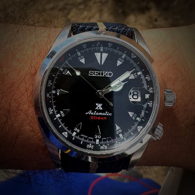 Close-up of a Seiko Prospex automatic 20-bar diver's watch with black dial and compass bezel, worn on a wrist with a navy NATO strap — representing the value of time as your most important asset.